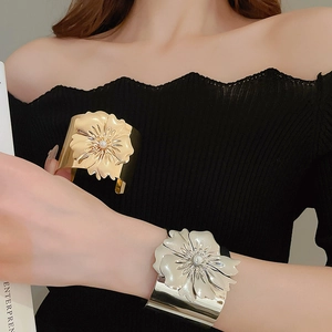 Detailed macro shot of large polished metal floral bangles with white pearl centers