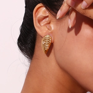 Gros plan macro de boucles d'oreilles coquillage dorées avec perles portées sur le mannequin