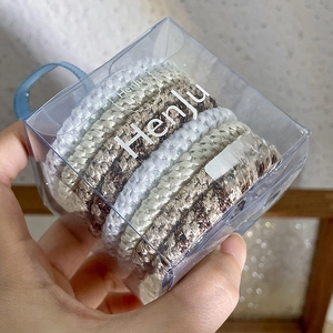 Close-up of durable woven hair ties with leopard print and solid colors in a clear box