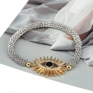 Bohemian silver beaded bracelet with a vintage golden evil eye and sunburst charm