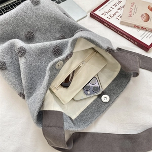 Dettaglio della borsa tote in lana grigia con pompon che mostra tasca e chiusura magnetica