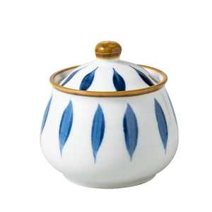 Hand-painted ceramic seasoning jar with blue leaves and brown trim on a white background