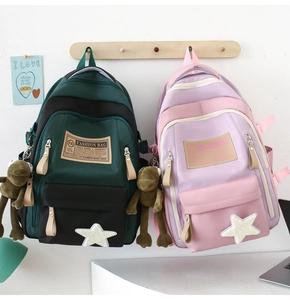 Close-up of contrast color school bag with star patch and plush frog charm detail