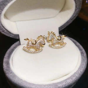 Detailed macro view of gold rocking horse stud earrings with sparkling cubic zirconia pavé