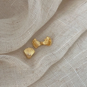 Orecchini a lobo a conchiglia minimalisti in argento 925 dorato su sfondo in tessuto bianco