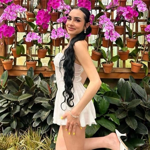Side view of a slim-fit white strapless mini dress on a model in an orchid garden