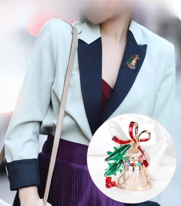 Detailed view of a gold Christmas bell brooch with red bow and colorful rhinestones