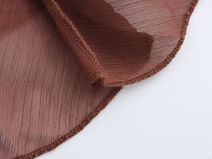 Macro dettaglio della trama in chiffon marrone a pieghe e della cucitura taglia-cuci rifinita