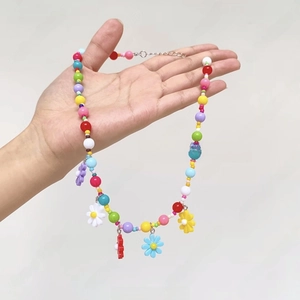 Close-up of colorful beaded necklace with floral charms and metal lobster clasp closure