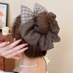 Detailed view of a brown plaid bow scrunchie on a dark brown bun hairstyle