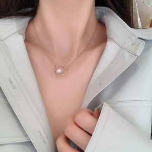 Minimalist gold necklace with wavy ring pendant and white pearl on female model