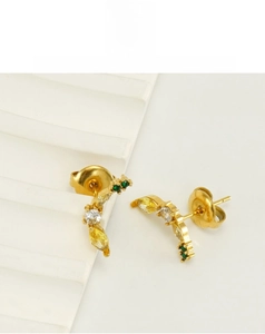 Gros plan de boucles d'oreilles banane dorées avec zircons jaunes et verts