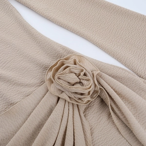 Detail view of khaki crepe fabric with 3D floral accents and elegant textured sewing