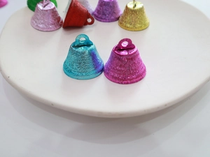 Close-up of 26mm colorful matte Christmas bells with glitter texture on white plate