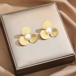 Elegant gold clover pearl stud earrings placed on a premium silk jewelry box