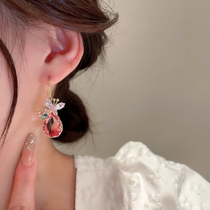 Gros plan de boucles d'oreilles dorées avec cristal rose et détails papillon chic
