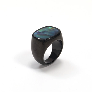 Macro view of black signet ring featuring iridescent abalone shell inlay on metal