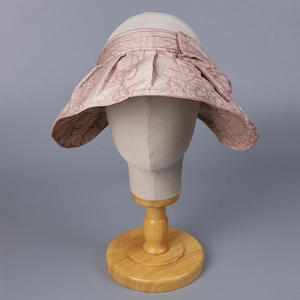 Detail of wide brim sun hat with elegant bow and vine patterns on pale pink fabric