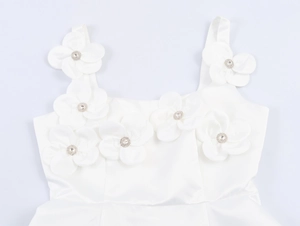 Dettaglio dell'abito in raso bianco con fiori 3D applicati e centri in strass brillanti