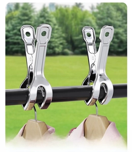 Polished stainless steel windproof clips securing hangers on a rod against outdoor background
