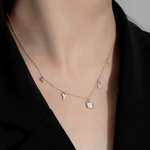 Detail of S925 sterling silver key and lock pendants on a delicate tassel necklace