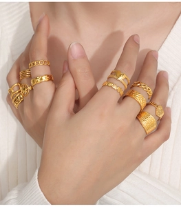 Detail shot of multiple gold-plated geometric rings with heart and woven textures on hands