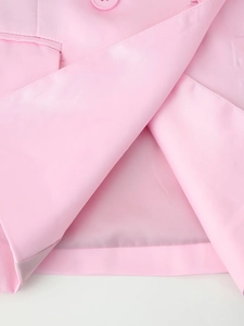 Detailed macro shot of pink satin blazer showing fabric texture, pocket flap, and matching button