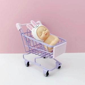 Miniature purple shopping cart desktop organizer with a sleeping baby doll figurine