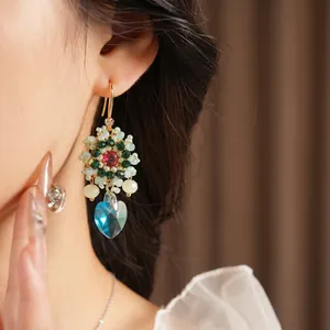 Vintage style floral beaded earrings with a blue heart crystal pendant on model