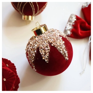 Detail of red velvet Christmas ball with intricate beadwork and gold metal hanger cap