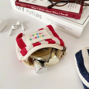 Detailed view of striped canvas makeup bag with lipstick inside on a clean desk setup
