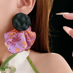 Close-up of vintage round irregular petal earrings with purple patterned fabric and black metal