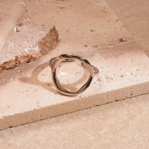 Close-up of irregular silver geometric ring on natural stone with metal texture