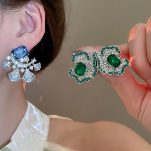 Detail shot of luxury flower earrings with deep blue and emerald green crystals