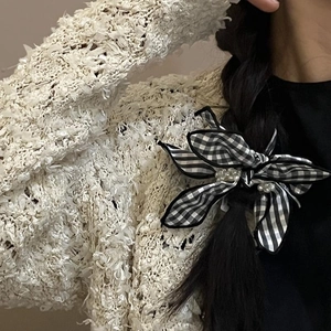 Classic black and white checkered bow scrunchie with faux pearl accents on a hair braid