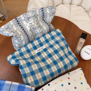 Checkered and floral fabric makeup bags displayed on a wooden table for storage