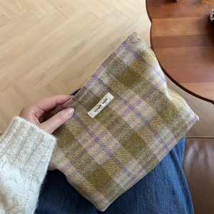 Detail of vintage plaid wool makeup bag with simple wish label on a cozy sweater background