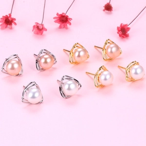 Macro view of triangle silver earrings with natural freshwater pearls on a pink background