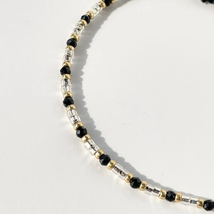 Macro shot of minimalist Miyuki glass beads and faceted black crystals on a thin bracelet