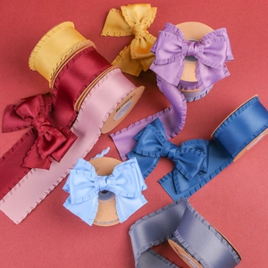 Rubans en satin plissés multicolores avec bords ondulés présentés sur des bobines