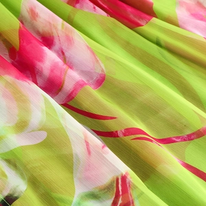 Détail du tissu plissé à imprimé floral vert citron et rose pêche pour robes d'été