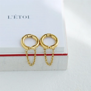 Polished gold fringe ear cuff with dangling chains displayed on a minimalist white card