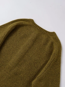Detailed close-up of moss green knit sweater showing ribbed crew neck and fuzzy texture