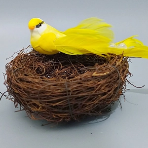 Close-up of a lifelike yellow artificial bird resting in a woven rattan bird nest