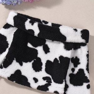 Close-up of soft faux fur fabric with black and white cow print texture and plush finish
