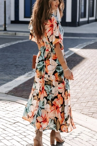 Detail of bohemian floral maxi dress featuring warm orange print and flowing high waist design