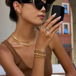 Close-up of elegant 14K gold and silver stainless steel layered jewelry worn by a model
