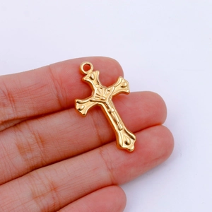 Detailed close-up of a layered gold cross pendant with intricate embossed religious motifs