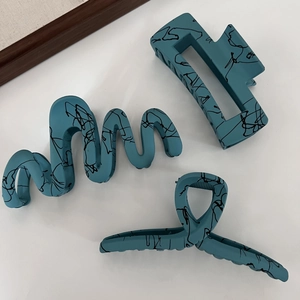 Matte blue hair clips with black ink splatter pattern in three geometric styles