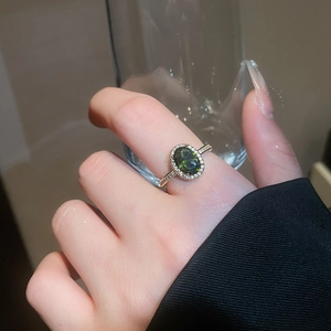 Close-up of 18k gold plated ring with oval green gemstone and zircon halo setting